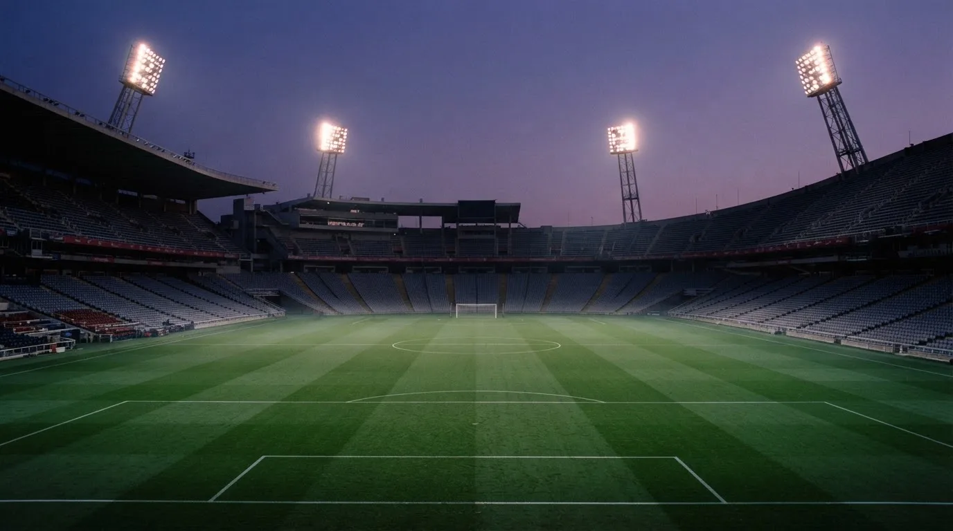 Een leeg voetbalstadion met lichtmasten bij schemering