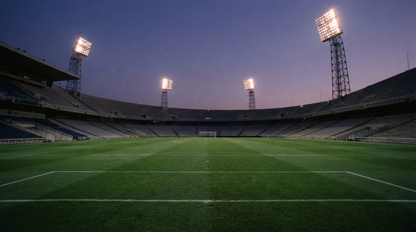 Een leeg voetbalstadion met lichtmasten bij schemering
