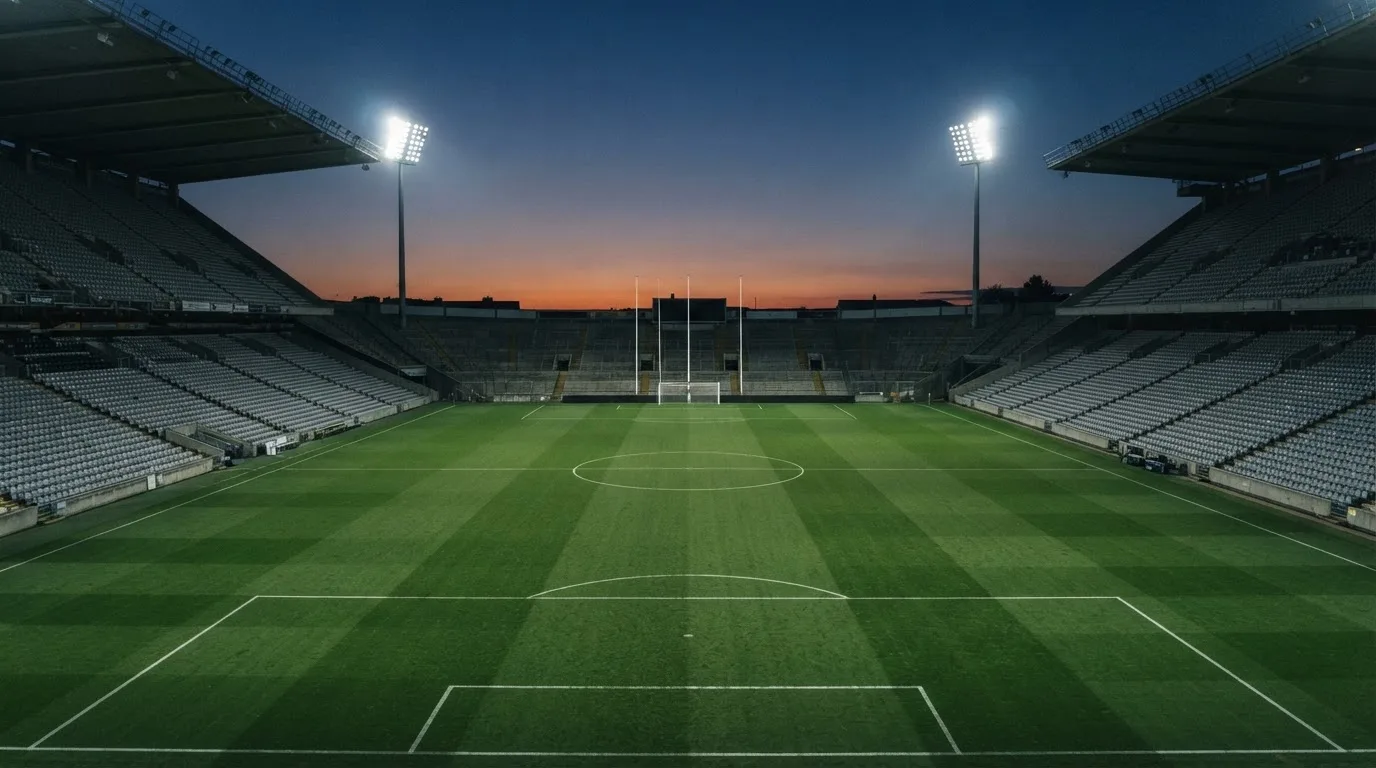 Een leeg voetbalstadion met lichtmasten bij schemering