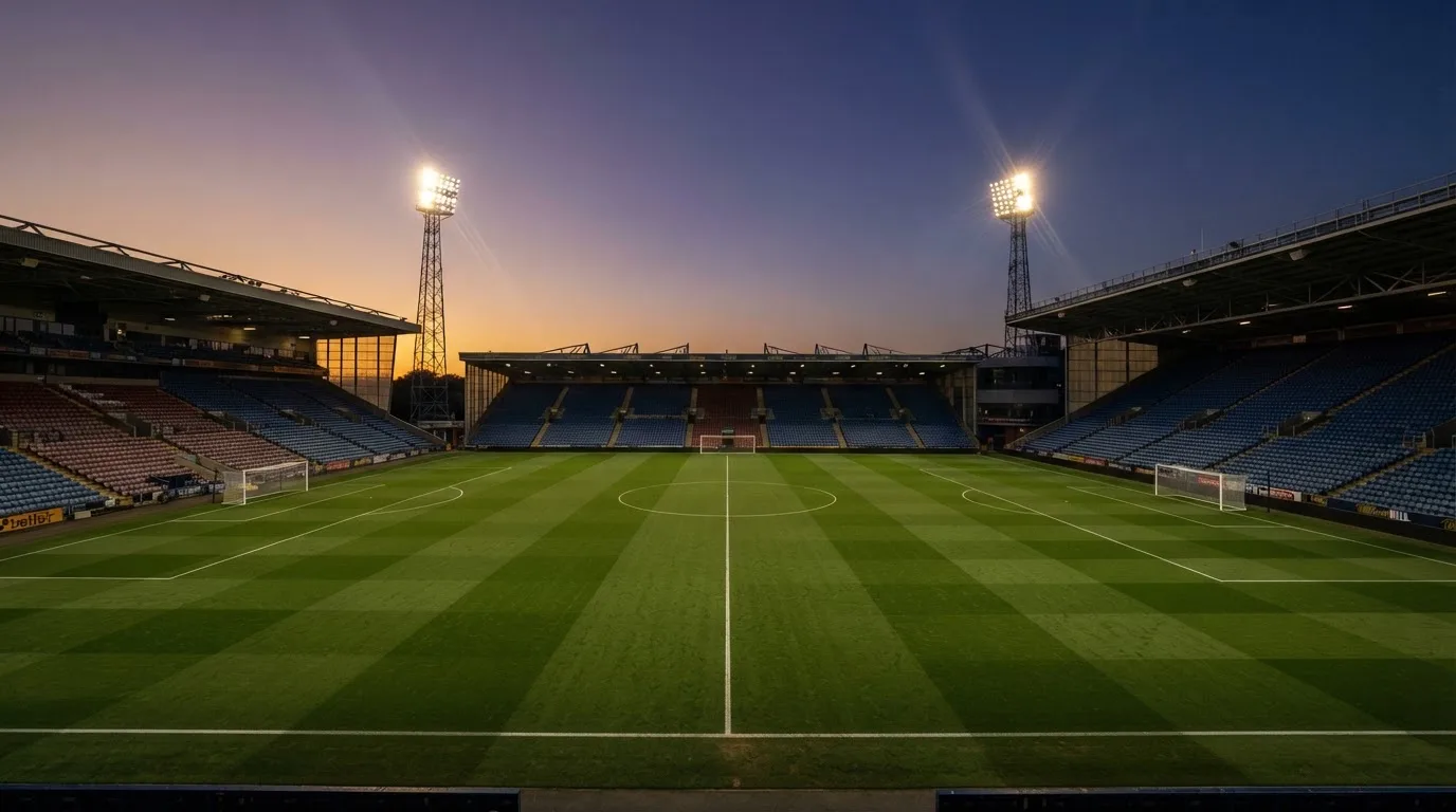 Een leeg voetbalstadion met lichtmasten bij schemering