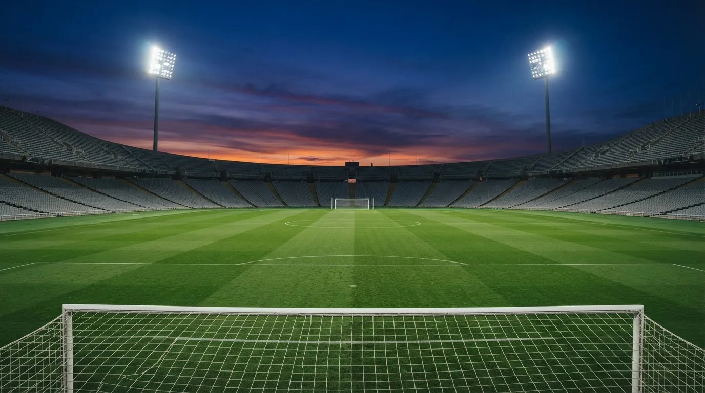 Een leeg voetbalstadion met lichtmasten bij schemering