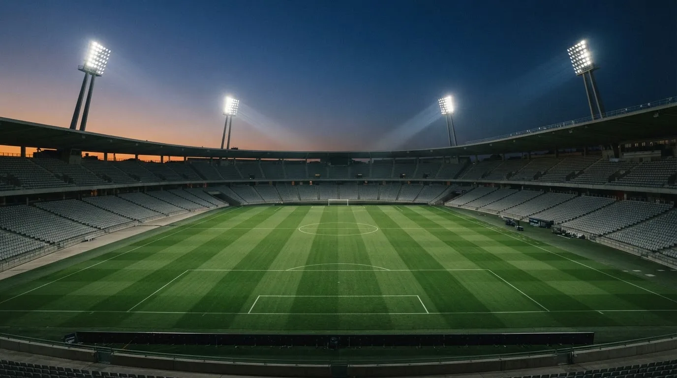 Een leeg voetbalstadion met lichtmasten bij schemering