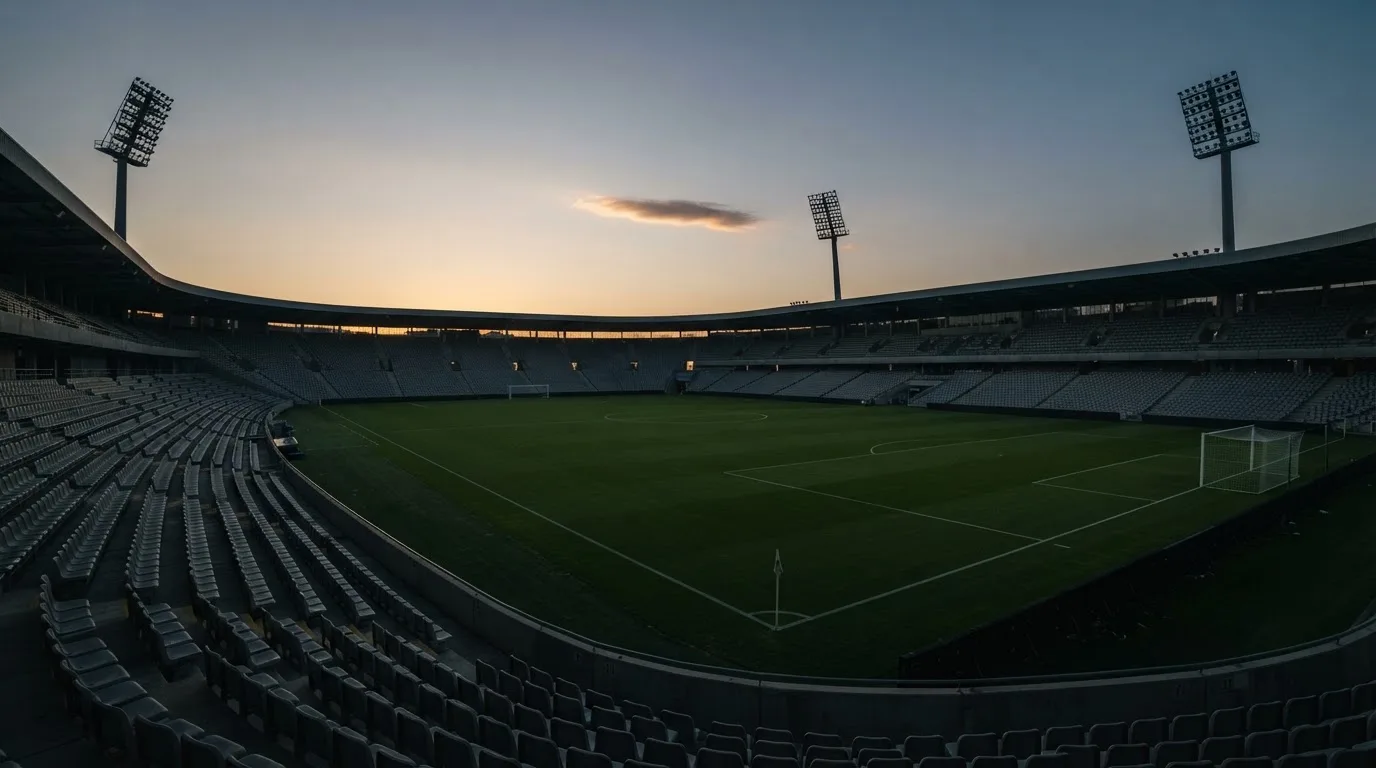 Een leeg voetbalstadion met lichtmasten bij schemering