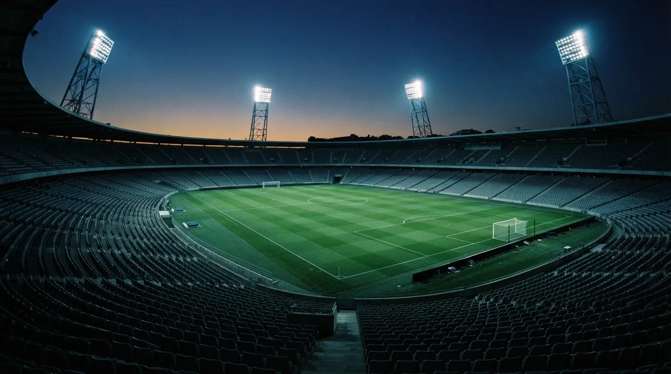 Een leeg voetbalstadion met lichtmasten bij schemering