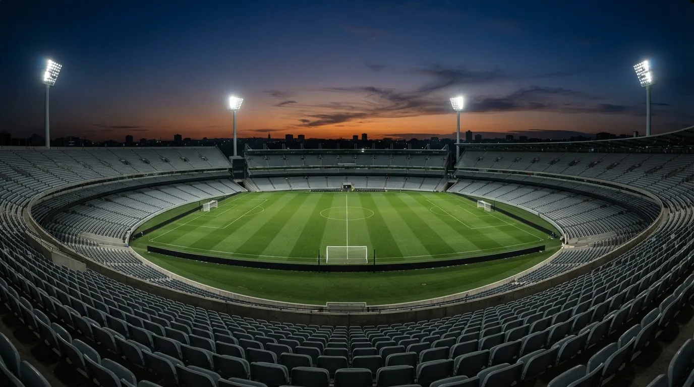 Een leeg voetbalstadion met lichtmasten bij schemering