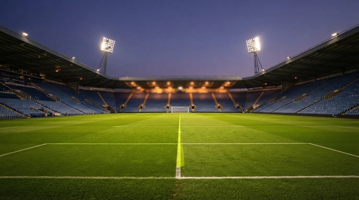 Een leeg voetbalstadion met lichtmasten bij schemering