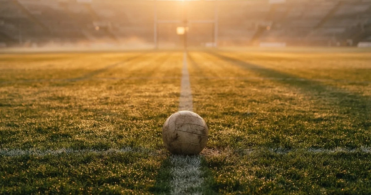 Een voetbal op de middenstip van een grasveld in het ochtendlicht
