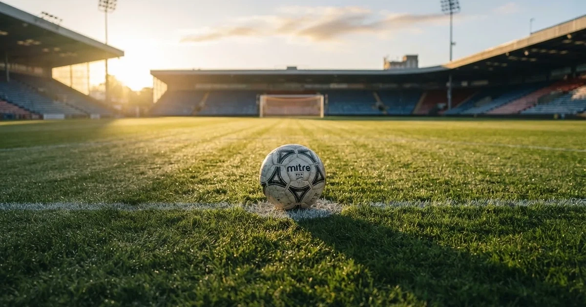 Een voetbal op de middenstip van een grasveld in het ochtendlicht