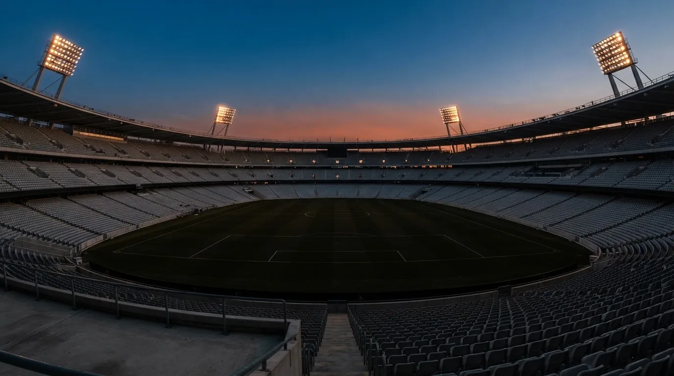 Een leeg voetbalstadion met lichtmasten bij schemering