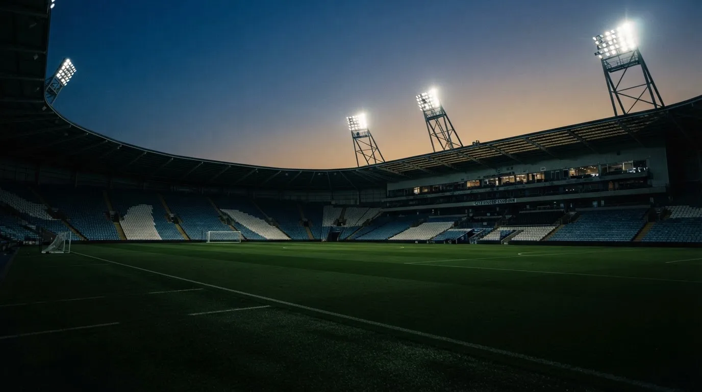 Een leeg voetbalstadion met lichtmasten bij schemering