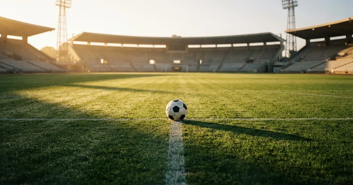 Een voetbal op de middenstip van een grasveld in het ochtendlicht